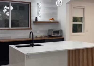 A contemporary kitchen featuring marble counter tops and a white island.